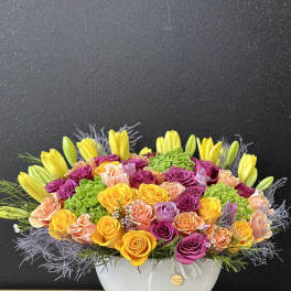 Bright mixed flower arrangement in a white bowl vase