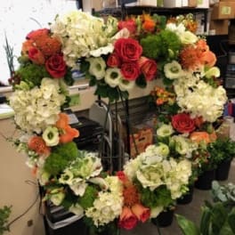Large floral wreath with red roses, white hydrangeas, and orange blooms
