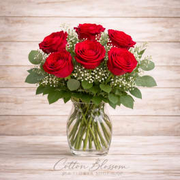 Red roses arranged in a clear glass vase with baby's breath