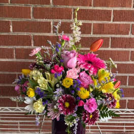 Mixed bouquet in a purple glass vase with pink, yellow, and white flowers