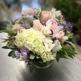 Bouquet of pale pink roses, white hydrangea, and purple flowers in a vase