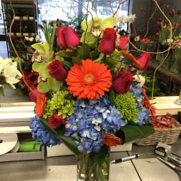 Bright mixed bouquet in a glass vase with roses, orchids, gerbera daisies, and hydrangeas