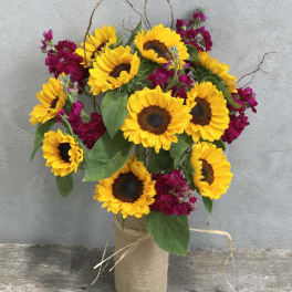 Sunflower bouquet with magenta flowers in a burlap-wrapped vase
