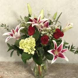Bouquet of pink lilies and red roses in a clear glass vase