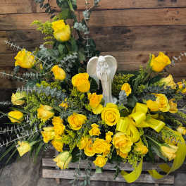 Yellow rose funeral spray with an angel figurine and ribbon