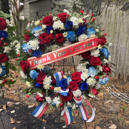 Red, white, and blue floral wreath on an easel with a thank-you ribbon