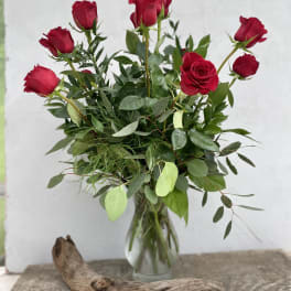 Red roses in a clear glass vase with mixed greenery
