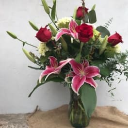 Bouquet of pink lilies and red roses in a glass vase