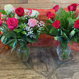 Two rose bouquets in glass vases with baby's breath