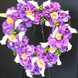 Heart-shaped floral wreath with purple flowers, white calla lilies, and yellow roses