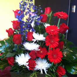 Mixed bouquet of red roses, red gerbera daisies, white spider mums, and blue delphinium