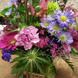 Mixed bouquet of purple daisies, pink carnation and gerbera in a clear glass cube vase