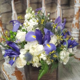 Purple irises and white hydrangeas in a rustic wooden box arrangement on a distressed chair