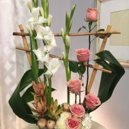 Tall floral arrangement with pink roses and white gladiolus in a rectangular vase