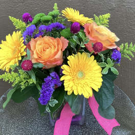 Bouquet of orange roses and yellow gerbera daisies in a glass vase