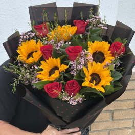 Bouquet of red roses and sunflowers wrapped in black paper