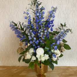 Tall blue and white floral arrangement in a gold vase