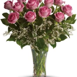 Arrangement of pink roses with white filler flowers in a clear glass vase