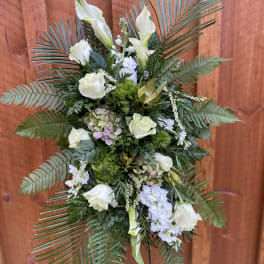 White floral standing spray with palm fronds and greenery