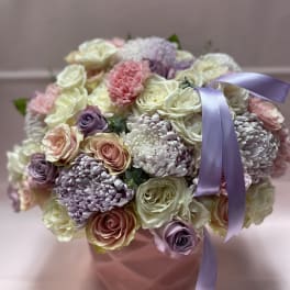 Bouquet of pastel roses and chrysanthemums in a pink box with a lavender ribbon