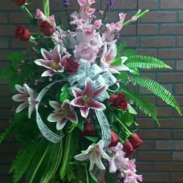 Standing floral spray with pink lilies, red roses, and purple spikes