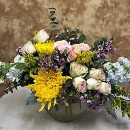 Mixed bouquet of roses, yellow chrysanthemums, and small purple flowers in a vase
