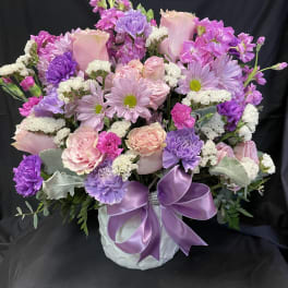 Pink and purple mixed bouquet in a white vase with a lavender ribbon