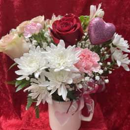 Bouquet of roses, chrysanthemums, and carnations in a white mug with a glitter heart