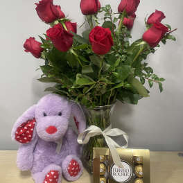 Red roses in a glass vase with a plush purple bunny and Ferrero Rocher chocolates