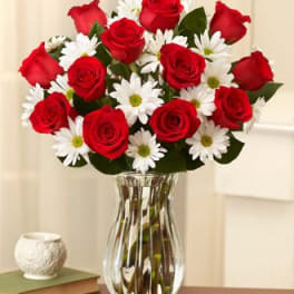 Red roses and white daisies in a clear glass vase