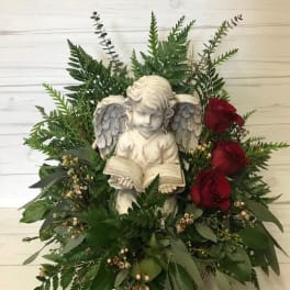 Angel statue surrounded by red roses and greenery