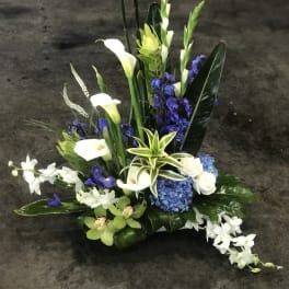 Tall floral arrangement with white calla lilies, blue hydrangea, and white orchids