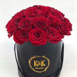 Red roses arranged in a black round hat box