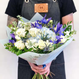 Handheld bouquet of white roses, blue hydrangea, and purple irises
