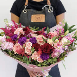 Large bouquet of pink, red, and purple flowers wrapped in pink paper