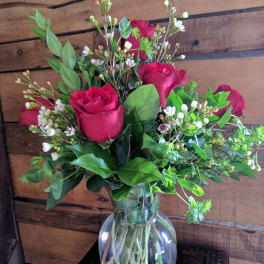 Bouquet of red roses and white filler flowers in a clear glass vase