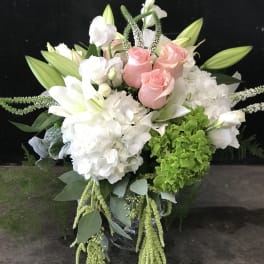Bouquet of pink roses, white lilies, and white hydrangeas with trailing greenery