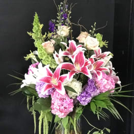 Tall bouquet of pink lilies, roses, and hydrangeas in a glass vase