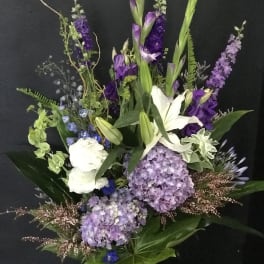 Tall bouquet of purple and white flowers with lilies and hydrangeas