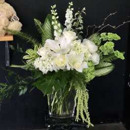 White lilies and hydrangeas arranged in a clear glass vase