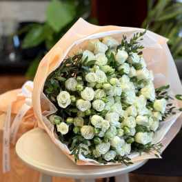 Bouquet of white spray roses wrapped in pale peach paper