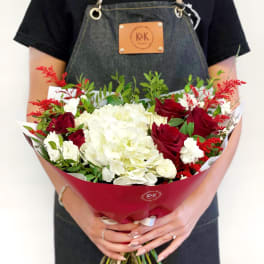 Bouquet of red roses and white hydrangeas wrapped in red paper