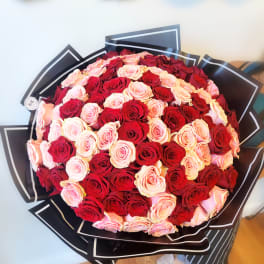 Large bouquet of red and blush pink roses wrapped in black paper