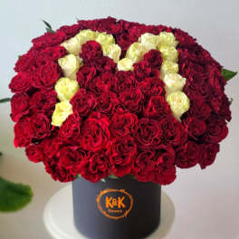 Red and cream roses arranged in a black hat box
