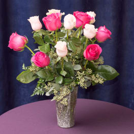 Pink and white roses arranged in a tall vase