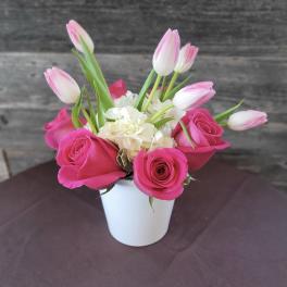 Pink roses and white tulips arranged in a white vase