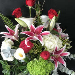 Bouquet of red roses, pink lilies, and white hydrangea in a glass vase