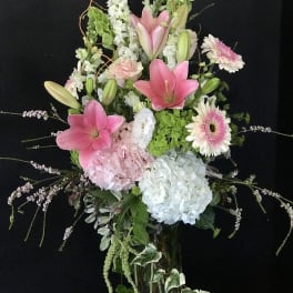 Tall pink and white floral arrangement in a glass vase