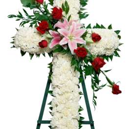 Tall white floral cross on a stand with red roses and pink lilies accents