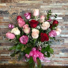 Bouquet of pink and red roses in a glass vase with a pink ribbon